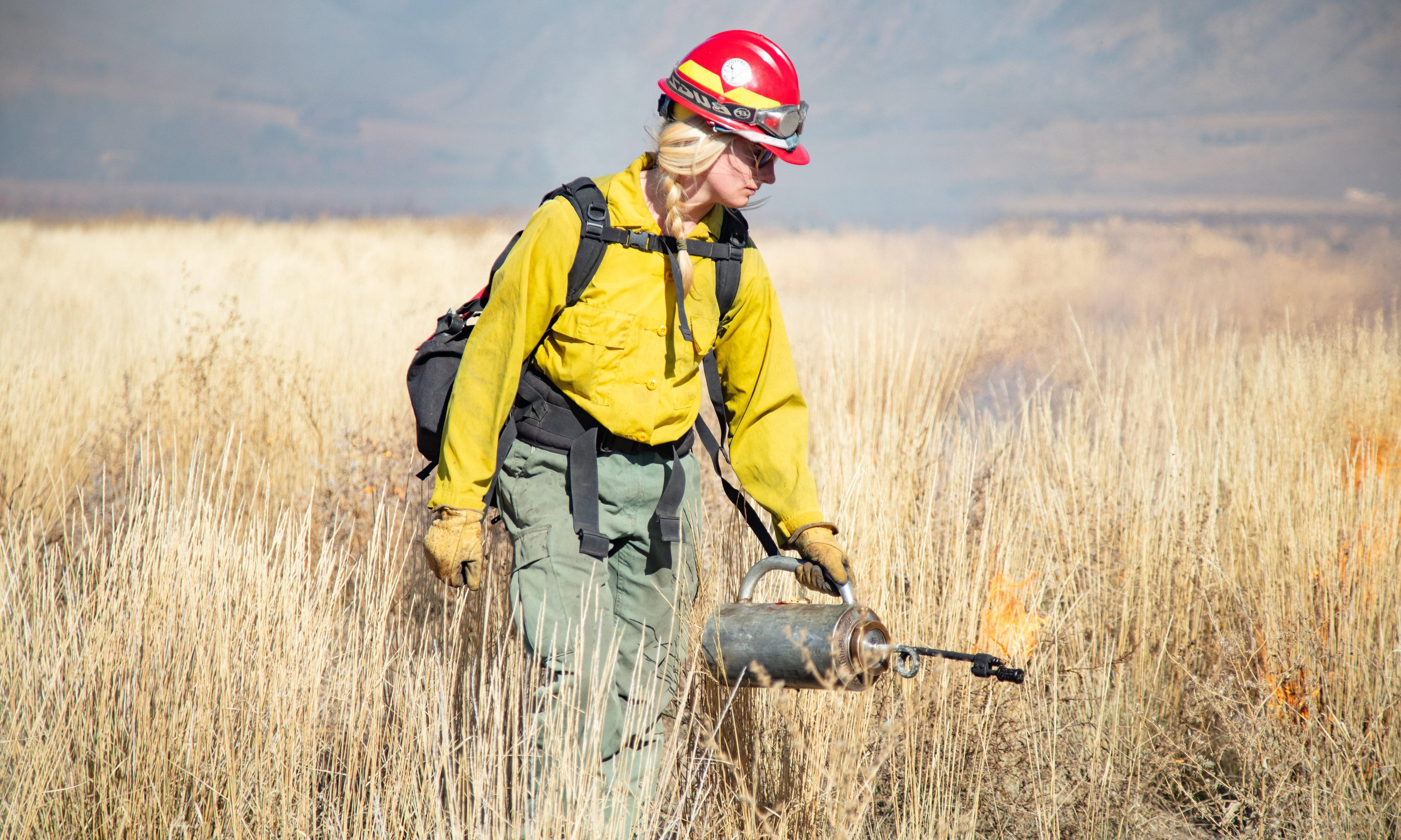 A firefighter carrying a drip torch